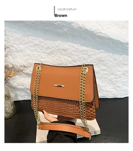 Detail of brown leather handbag featuring gold chain strap and crocodile embossed texture