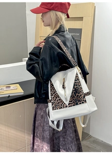 Detailed side view of leopard print backpack with white leather and metal zipper accents