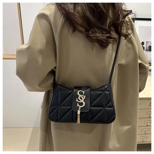 Close-up of black quilted crescent bag with golden S-shaped buckle and fringe detail