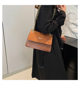 Detail of a brown two-tone chain bag featuring smooth leather and crocodile texture