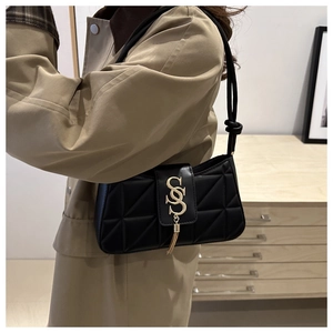Close-up of quilted black crossbody bag featuring gold SS logo and elegant tassel detail