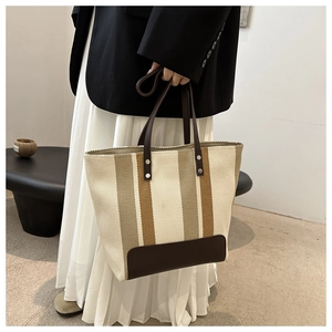 Close-up of vertical striped woven tote bag with premium brown leather trim and handles