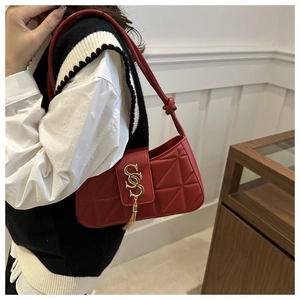 Detailed close-up of red quilted shoulder bag with gold tassel buckle and chain strap