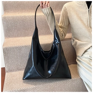 Close-up of a glossy black patent leather tote bag in a stylish lifestyle setting