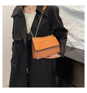 Detail of vintage brown shoulder bag with crocodile pattern and golden metal buckle clasp