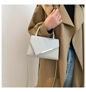 Detail of grey PU leather shoulder bag with glitter V-flap and gold metal accents