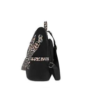 Detail of leopard print straps and side pockets on a black nylon backpack with gold hardware