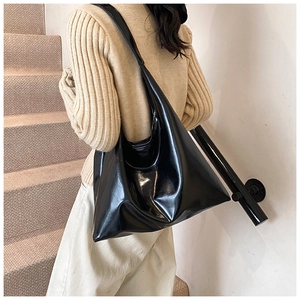 Detail shot of large black patent leather tote bag showing glossy texture and slouchy shape