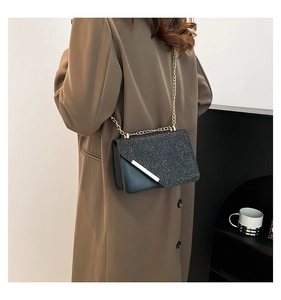 Detail of black glitter crossbody bag with gold chain worn on long coffee coat