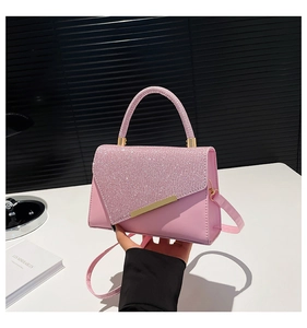Detailed view of pink glitter flap bag with golden metal hardware and top handle strap