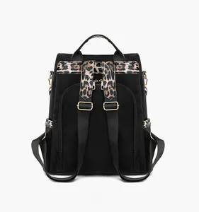 Detail view of black nylon backpack back with leopard print straps and gold metal buckles
