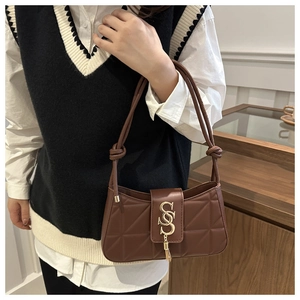 Close-up of brown quilted shoulder bag with gold metal S letter and tassel detail