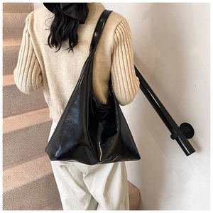 Detail shot of a minimalist black glossy hobo shoulder bag with smooth patent leather texture
