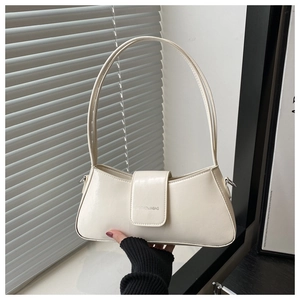 Detail of minimalist cream baguette bag featuring embossed logo and slim double straps