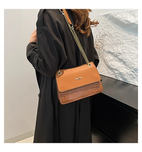 Rear view of model wearing a brown crocodile-embossed leather bag with gold chain