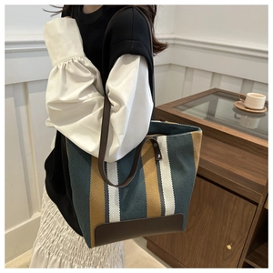 Detailed view of striped canvas tote with leather straps and reinforced bottom