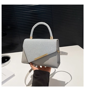 Close-up of silver PU leather handbag featuring glitter rhinestones and gold metal buckle