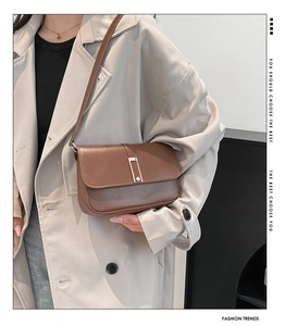 Borsa a tracolla marrone con fibbia dorata abbinata a un trench coat beige chiaro