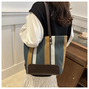 Detail of striped canvas tote bag with leather handles and reinforced metal rivets