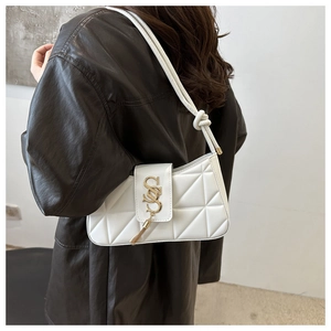 Close-up of white quilted handbag with golden SS logo and metallic tassel detail