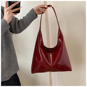 Close-up of deep wine red glossy leather hobo bag with sleek minimalist shoulder strap