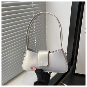 Close-up of pearl white leather baguette bag with minimalist flap and shoulder strap