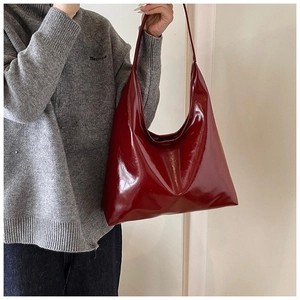 Detail of burgundy patent leather hobo bag with glossy finish on shoulder