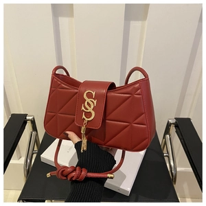 Detail of burgundy quilted leather handbag with gold tassel and letter hardware