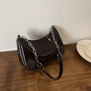 Close-up of glossy dark brown crescent bag with polished silver metal chain strap