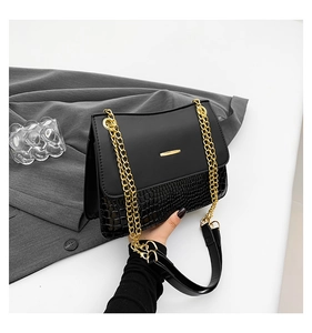 Detailed shot of black crocodile embossed shoulder bag with gold chain strap