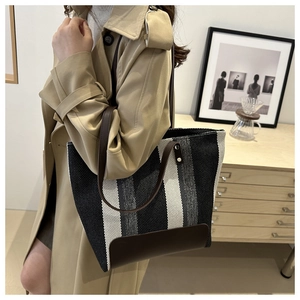 Detailed side view of large woven tote bag with gray stripes and leather handles