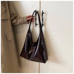 Detail of a glossy chocolate brown minimalist hobo shoulder bag with a wide strap