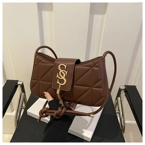 Detail of quilted brown leather texture with golden S-logo hardware and tassel charm