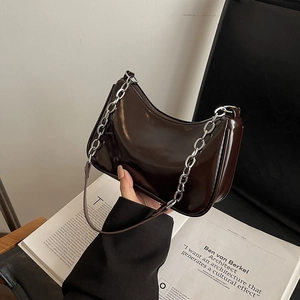 Detail of dark brown patent leather underarm bag with silver chunky chain accent