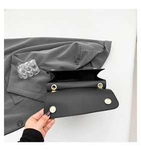 Detail of black leather shoulder bag with gold magnetic buckle and interior compartment