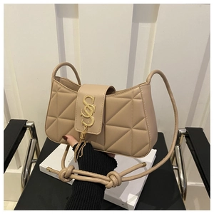 Close-up of beige quilted crossbody bag with gold metal logo and tassel detail