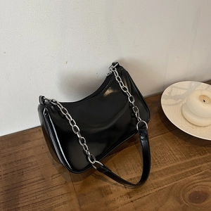Detailed view of black patent leather hobo bag with thick silver metal chain strap