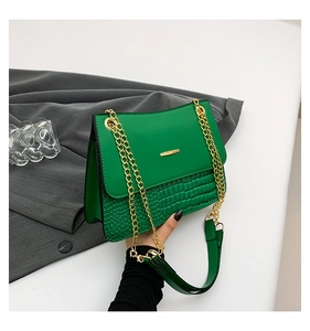 Close-up of green crocodile embossed faux leather with gold chain strap detail
