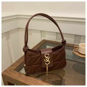 Close-up of dark brown quilted shoulder bag with golden logo and tassel detail