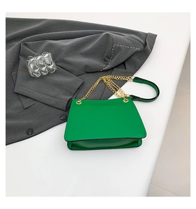 Detail of bright green leather flap bag with elegant gold chain strap and shoulder pad