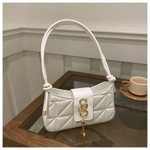 Detail of white quilted faux leather bag with gold SS hardware and tassel on a table