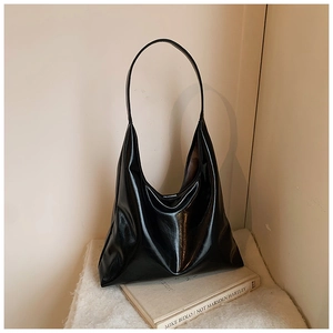 Detail of the black patent leather texture and spacious interior of the shoulder tote bag