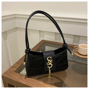 Detail of black quilted shoulder bag featuring gold S letter logo and tassel charm