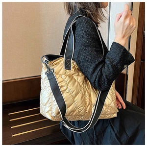Detail of gold quilted tote bag with metallic finish and contrast woven handles
