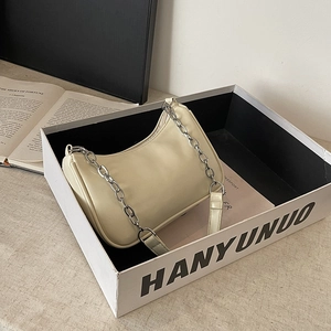 Detail view of cream shoulder bag with stylish silver chain strap and minimalist box