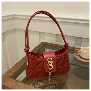 Close-up of red quilted leather bag with gold SS letter logo and metallic tassel detail