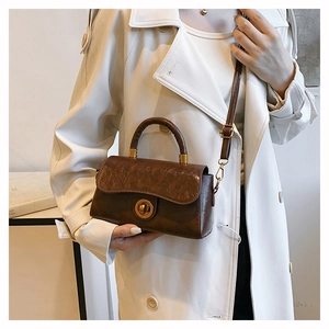Detail of vintage brown leather handbag with gold twist-lock and slim shoulder strap