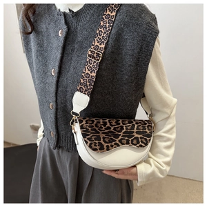 Detail of a white saddle bag with leopard print flap and wide adjustable shoulder strap