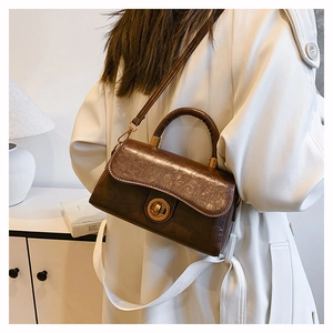 Detail of dark brown leather handbag with gold metal lock and round handle