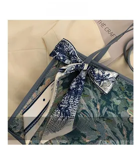 Détail du sac cabas en jacquard floral avec bordure en cuir bleu et ruban en soie